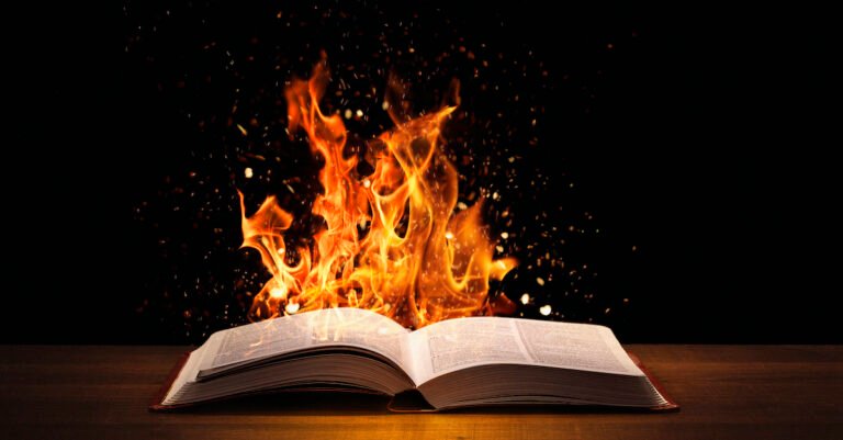 Holy Bible on fire on a wooded desk